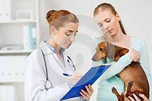 Woman with dog and doctor at vet clinic