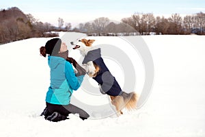 Woman and dog have fun while the walk, snowy winter landscape