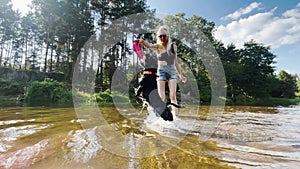 A woman and a dog playing with frisbee on the river