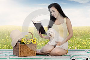 Woman and dog read book on meadow