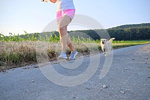 Woman with a dog running down a gravel street