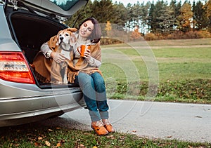 Woman with dog sit together in cat truck and warms hot tea photo