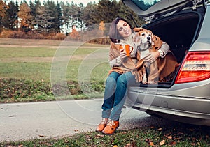 Woman with dog sit together in cat truck and warms hot tea photo