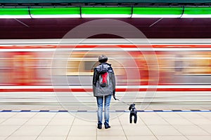 Woman with dog at subway station with blurry moving train