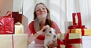 Woman with dog video call with camera among christmas gifts