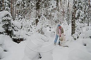 Woman with a dog on walk in a winter wood