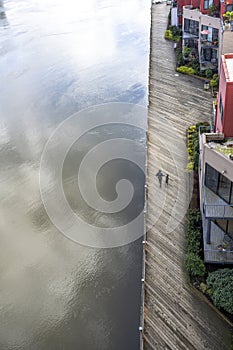 Woman with a dog walking along a wooden promenade along the Willamette River in Portland