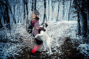 woman with dog walking in frost covered forest in winte