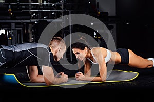 Woman doing abdominal crunches press exercise on the mat with her sports male trainer.