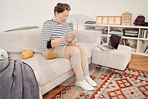 Woman doing activities in a retirement house while sitting at the sofa and knitting