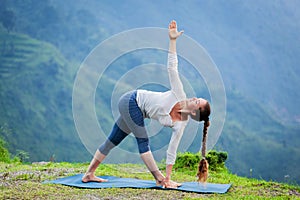 Woman doing Ashtanga Vinyasa yoga asana Parivrtta trikonasana