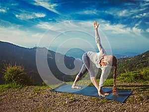 Woman doing Ashtanga Vinyasa yoga asana Parivrtta trikonasana