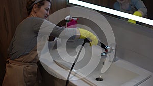 Woman doing bathroom cleaning at home, female washing tile wall with steam. Using steam cleaner for quick cleaning