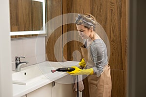 Woman doing bathroom cleaning at home, female washing tile wall with steam. Using steam cleaner for quick cleaning