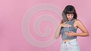 Woman doing a Breast Self-Exam over pink background.