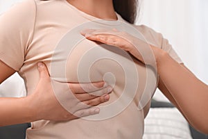 Woman doing breast self-examination at home, closeup