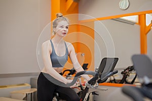 Woman doing cardio workout biking training in indoors gym