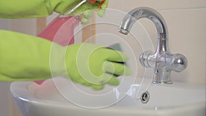 Woman doing chores in bathroom at home, cleaning sink and faucet with spray detergent. Sequence