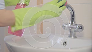 Woman doing chores in bathroom at home, cleaning sink and faucet with spray detergent. Sequence