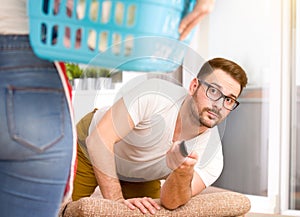 Woman doing chores while man watching tv