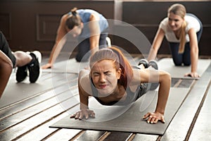 Woman doing difficult plank exercise or pushups at group trainin