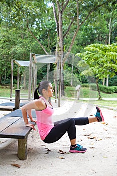Woman doing dips on right leg in outdoor exercise park