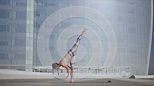 Woman doing downward facing dog pose. Girl performing yoga exercises on street