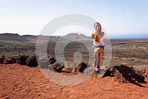 Woman doing eagle yoga pose on rock at Timanfaya National Park