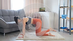 Woman is doing exercise for booty and glutes standing on all fours at home.