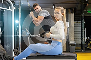 Woman doing exercise with cable rowing crossover machine at the gym.