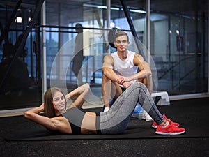 A woman doing an exercise on a floor and on a background of a gym. Training and sports concept. Copy space.