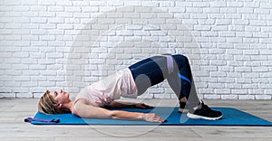 Woman doing exercise for glute hip bridge abduction using rubber resistance band