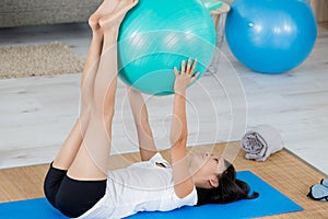 Woman doing exercise routine at home with aerobic ball