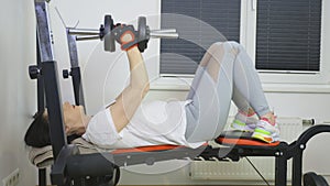 Woman doing exercises with dumbbells on bench