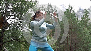 A woman is doing exercises in the mountains, she is engaged in meditation and yoga. Healthy lifestyle. slow motion