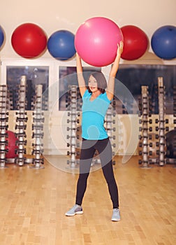 Woman doing exercises with pink fit ball in fitness gym class. Fitness ball helps women get a toned, tight stomach and strong core