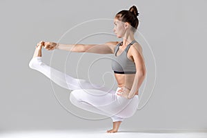 Woman doing Extended Hand to Big Toe pose with squat