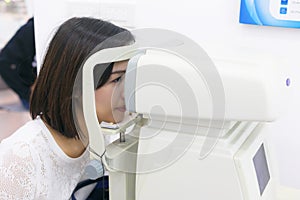 Woman doing eye test with optometrist machine in eye sight clinic. photo