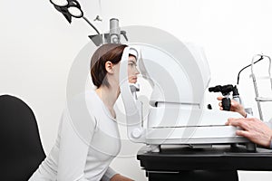 Woman doing eyesight measurement with optician slit lamp photo