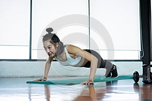 Woman doing fitness training. Fitness woman doing push ups on a training mat. young woman doing push-ups at the gym. Muscular