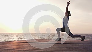 Woman doing fitness workout at sunset by the sea.