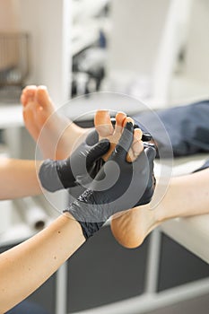 Woman doing foot peeling in pedicure SPA salon. Sugar scrub and relax beauty procedure