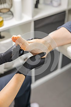 Woman doing foot peeling in pedicure SPA salon. Sugar scrub and relax beauty procedure