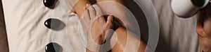 Woman doing foot spa treatment with stones and oil indoors