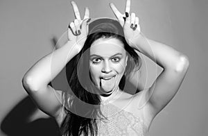 Woman doing funny gesture with finger over head as bull horns. Crazy funny sexy girl doing funny gesture with finger