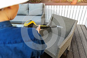 Woman doing garden terrace furniture cleaning with high pressure washer