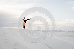 Woman doing a handstand at White Sands National Monument in Alamogordo, New Mexico.