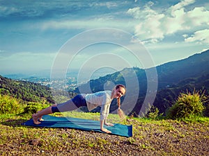 Woman doing Hatha yoga asana plank pose outdoors