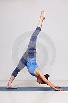 Woman doing Hatha yoga Eka pada adhomukha svanasana