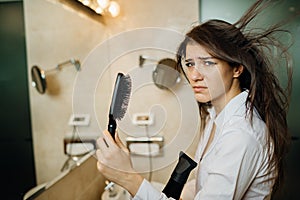 Woman doing her hair styling with a brush at home.Bad hair day